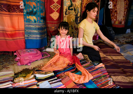 Femme et sa fille avec des produits textiles au marché de nuit à Luang Prabang au Laos Banque D'Images