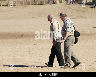Deux vieux hommes marchant sur une plage de sable Banque D'Images