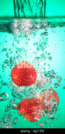 Les fraises de tomber dans l'eau coloré Banque D'Images