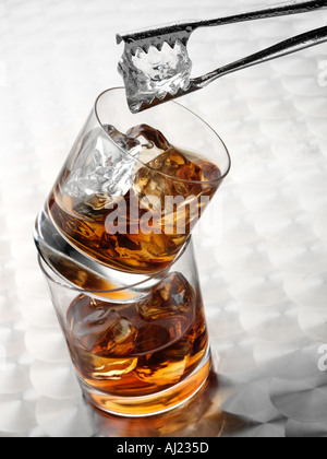 Dans deux verres de whisky en équilibre SUR L'AUTRE. Avec de la glace et des pinces Banque D'Images