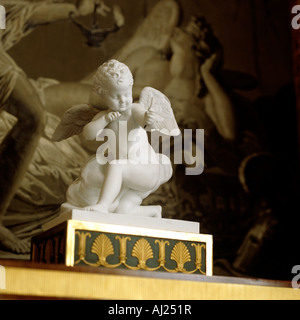 Statue en marbre blanc sur socle orné de chérubin avec art religieux en arrière-plan Banque D'Images