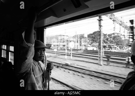 L'Indonésie Jakarta passagers assis par porte ouverte de trains de banlieue bondés à Kota Railway Station pendant l'heure de pointe du matin Banque D'Images