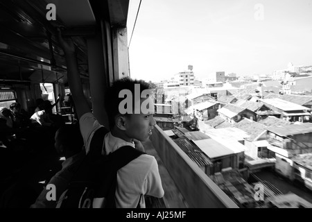 L'Indonésie Jakarta passagers assis par porte ouverte de trains de banlieue bondés à Kota Railway Station pendant l'heure de pointe du matin Banque D'Images