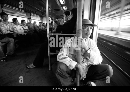 L'Indonésie Jakarta passagers assis par porte ouverte de trains de banlieue bondés à Kota Railway Station pendant l'heure de pointe du matin Banque D'Images