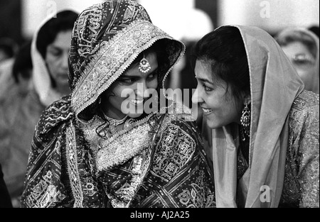 Mariée Sikh (à gauche) avec la petite amie dans la salle de prière du temple pendant le mariage d'une cérémonie à Gurdwara, Hounslow, Middlesex, Angleterre. Banque D'Images