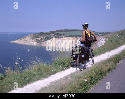 Jeune femme parution du modèle de l'île de Wight en tournée cycliste s'arrête pour admirer une vue sur la baie d'alun sur une chaude journée d'été Banque D'Images