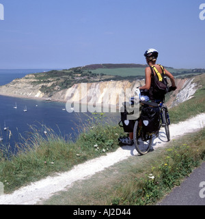 Jeune femme parution du modèle de l'île de Wight en tournée cycliste s'arrête pour admirer une vue sur la baie d'alun sur une chaude journée d'été Banque D'Images