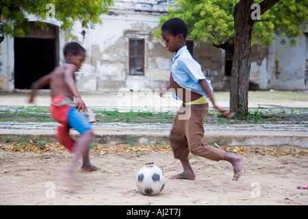 Les garçons jouent au football entre les maisons coloniales délabrées sur Ilha do Mozambique Banque D'Images