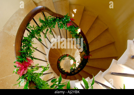 Un escalier en pierre en spirale avec une rampe en bois décoré de feuilles et de fleurs pour une cérémonie de mariage Banque D'Images