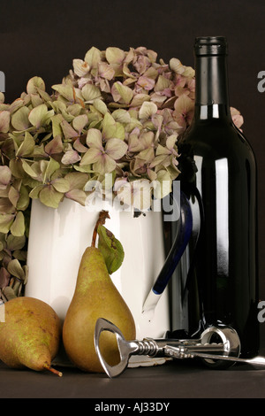 L'Hydrangea fleurs disposés dans un pot émaillé avec deux Poires au vin rouge bouteille et tire bouchon Banque D'Images