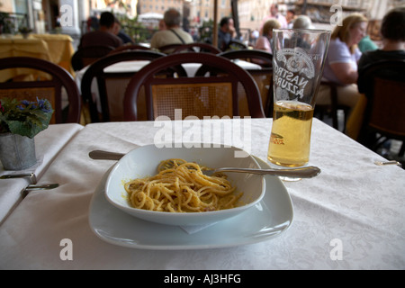 À moitié mangé bol de Spaghetti Carbonara et verre de bière assis sur une table dans un café de la rue de la Piazza Navona Banque D'Images