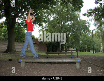 Jeune femme orientale coréenne slim équilibrer de manière optimale sur les feux dans le parc à Clapham Londres UK Banque D'Images