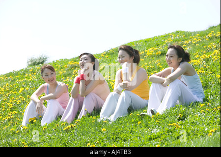 Quatre jeunes Woman sitting in field Banque D'Images