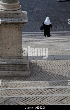 Une religieuse en habit complet walking down steep étapes colonne passé Rome Lazio Italie Banque D'Images