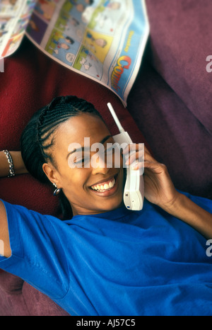 African American Woman relaxing on coach tout en parlant sur téléphone portable Banque D'Images