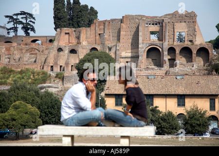 Un couple italien s'asseoir en face de l'autre en face de l'Circus Maximus et le palais impérial sur le mont Palatin, Rome, Latium Banque D'Images