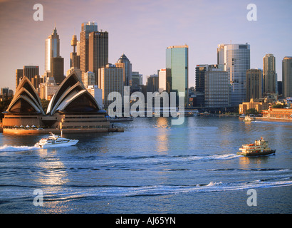 Des taxis bateau traversant le Port de Sydney avec l'Opéra et de la skyline at dawn Banque D'Images