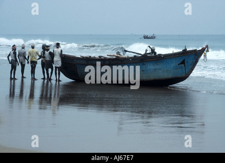 Les pêcheurs se préparent à lancer leur bateau à partir de la plage à l'aube Banque D'Images