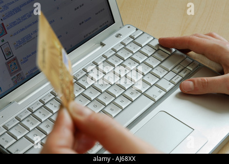 Close up montrant les mains sur le clavier holding credit card alors que les achats en ligne avec un ordinateur portable Banque D'Images