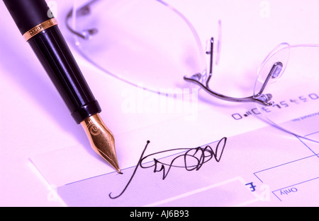 Gros plan de la signature d'écriture avec un stylo plume sur un vérifier Banque D'Images