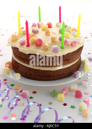Un gâteau d'anniversaire avec des bougies et de banderoles sur un fond blanc Banque D'Images