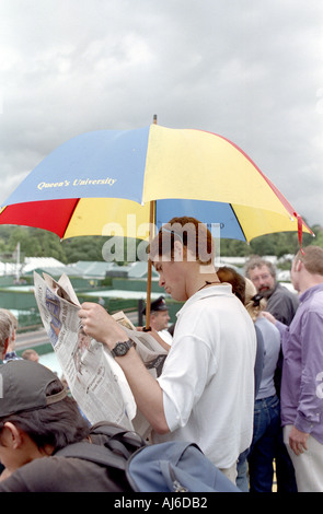 L'homme lit Journal au tournoi de tennis de Wimbledon à Londres UK Banque D'Images