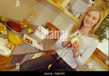 Young woman peeling une pomme dans la cuisine. Banque D'Images