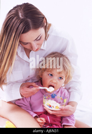 Une femme l'alimentation d'une petite fille. Banque D'Images