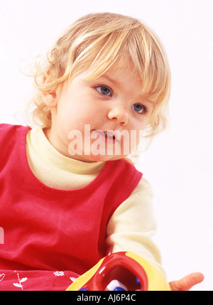 Tout-petit enfant 0 5 peau claire dodus juste juste aux cheveux bouclés blonds visage rond bent intéressé jouer Banque D'Images