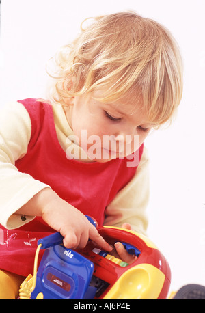 Tout-petit enfant 0 5 peau claire dodus juste juste aux cheveux bouclés blonds bent concentrer jouer jouer toy Banque D'Images