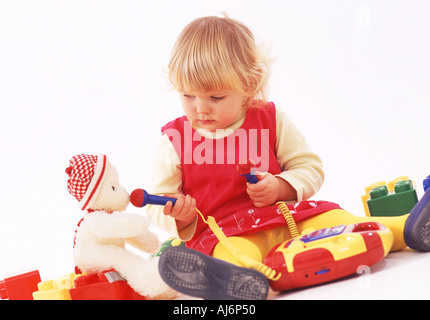 Tout-petit enfant 0 5 peau claire dodus juste juste aux cheveux bouclés blonds bent concentrer jouer jouer toy Banque D'Images