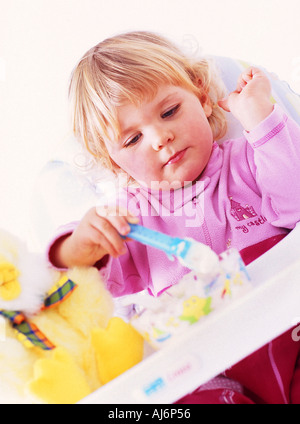 Tout-petit enfant 0 5 peau claire dodus juste juste aux cheveux bouclés blonds babygro asseoir l'appétit de nourriture manger Banque D'Images