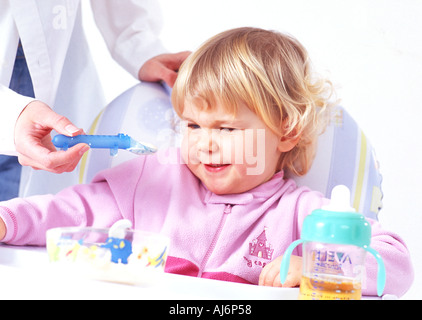 Tout-petit enfant 0 5 peau claire dodus juste juste aux cheveux bouclés blonds babygro asseoir l'appétit de nourriture manger Banque D'Images