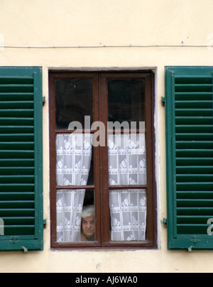 Femme âgée peeking out window Italie Banque D'Images