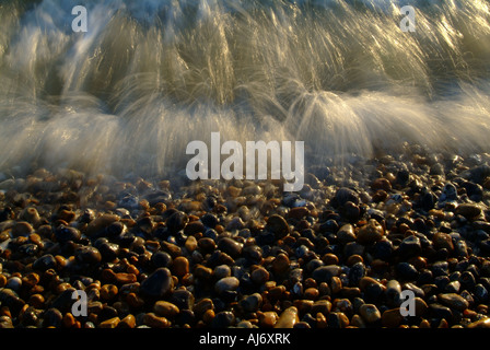 Une vague s'écraser sur une plage de Stoney à Brighton East Sussex Angleterre prise avec une exposition lente Banque D'Images