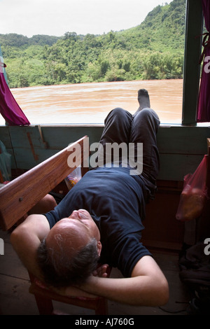 Ses pieds passager se bloque à partir de la fenêtre sur le bateau lent entre Luang Prabang et Huay Xai sur le Mékong au Laos Banque D'Images