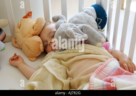 Bébé endormi heureux entouré de teddies Banque D'Images