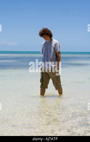 Teenage boy walking dans les eaux tropicales peu profondes Banque D'Images