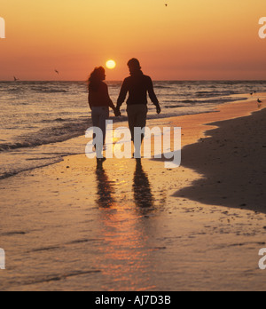 Couple walking on tropical beach at sunset Banque D'Images