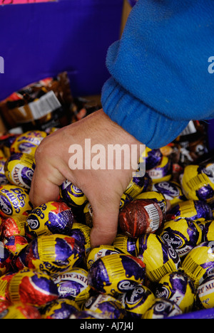 L'homme en saisissant une poignée de mini-oeufs de pâques en vente en magasin du village Banque D'Images