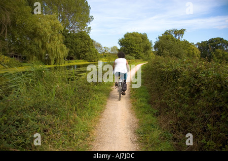 Des cycles d'une femme par le chemin de halage du canal de l'Exeter, Exeter, Devon, UK. Banque D'Images