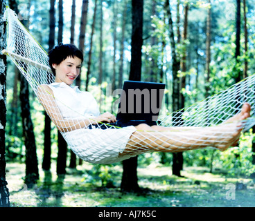 Femme assise dans un hamac et en utilisant son ordinateur. Banque D'Images