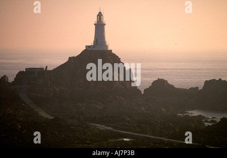 Corbiere lighthouse reste ferme sur les rochers à marée basse en fin d'après-midi, soleil d'été La Pulente Jersey UK Premier phare à être construit de béton Banque D'Images