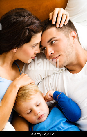 Les parents de race blanche de câlins avec petit garçon sleeping in bed Banque D'Images