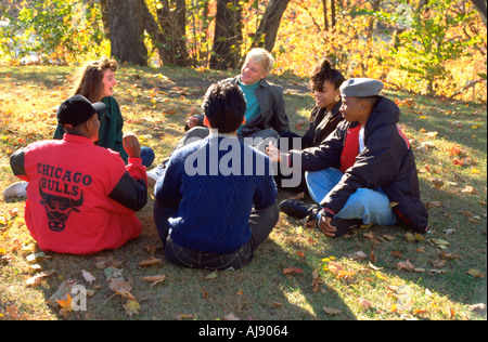 Groupe multi-ethnique de l'école secondaire de 15 ans d'amis assis en cercle en parlant du parc de la ville. St Paul Minnesota USA Banque D'Images