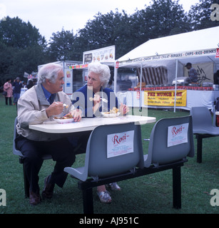 Un couple s'asseoir pour déguster un curry à la Newcastle Mela, Royaume-Uni. Banque D'Images