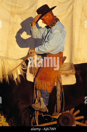 Un chapeau de cowboy ajuste son cheval sur le chemin du retour au camp. Banque D'Images