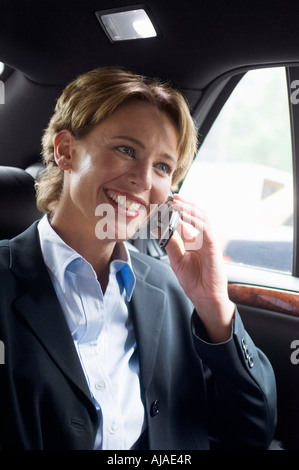 Businesswoman Using Cellular Phone in Car Banque D'Images