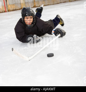 Garçon, joueur de hockey sur glace en uniforme sur la glace coulissante holding stick vers puck Banque D'Images