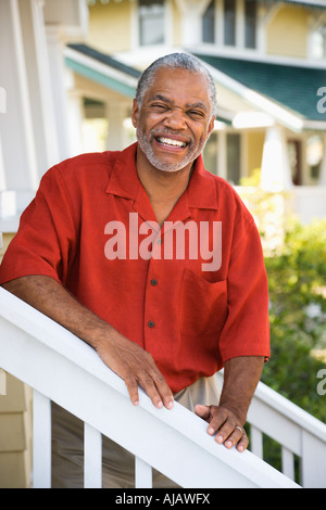 African American middle aged man smiling at viewer and leaning on railing escalier Banque D'Images